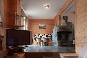 A modern interior with a TV, dining area, and stone fireplace. - Chalet “Eden” with Balcony and Wi-Fi (Les Belleville)