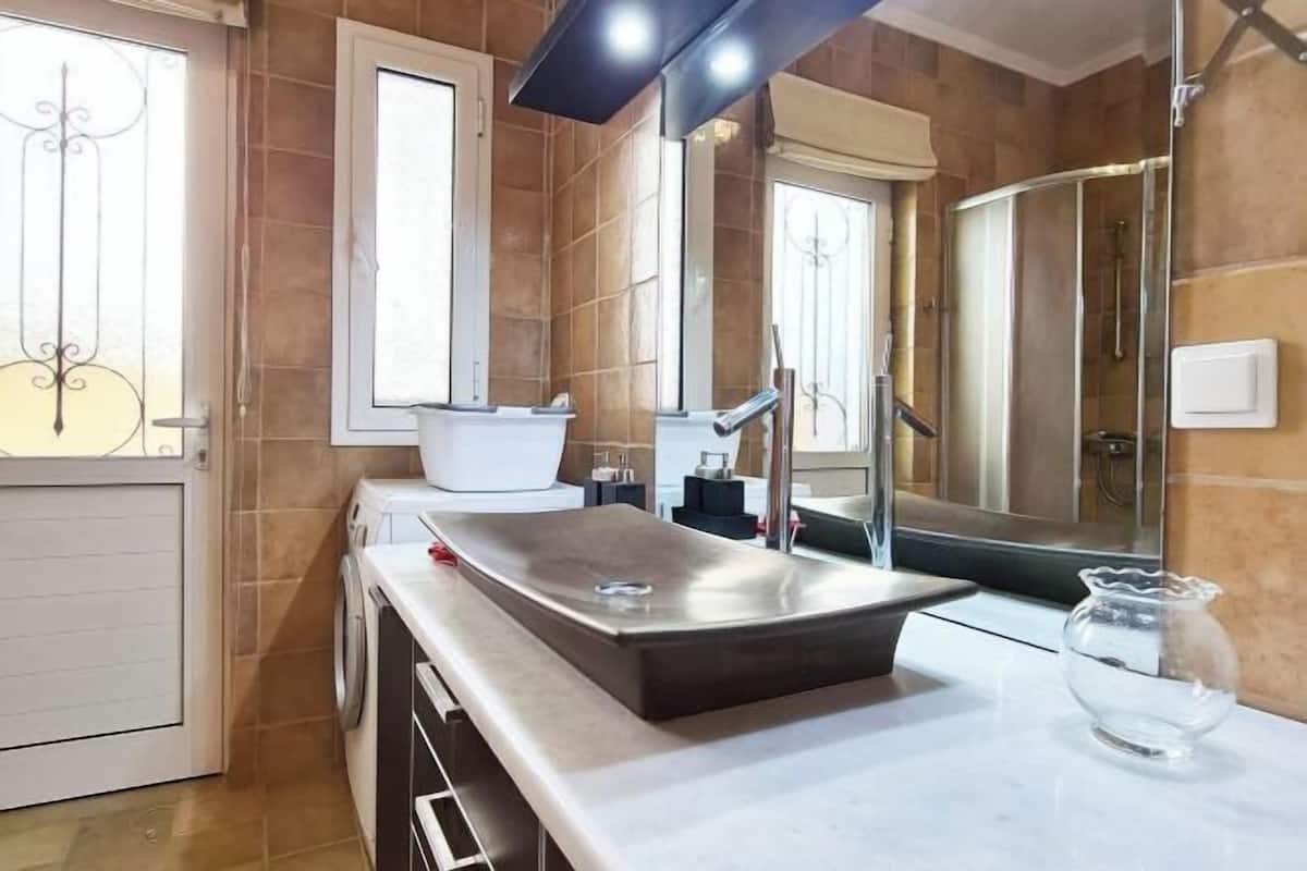 A modern bathroom with a large mirror, a sink, and a shower area.
