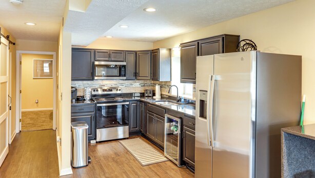 A modern kitchen with stainless steel appliances, dark wooden cabinets, and a granite countertop. - Townhome: Bunk Room for 6, Dry Bar Lounge Area (Cincinnati)