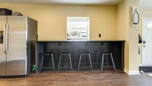 A kitchen with a stainless steel refrigerator, a window above the counter, and three stools. - Townhome: Bunk Room for 6, Dry Bar Lounge Area (Cincinnati)