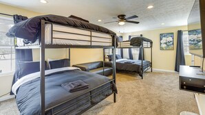 A bunk bed room with a ceiling fan, a desk, and a window with curtains. - Townhome: Bunk Room for 6, Dry Bar Lounge Area (Cincinnati)