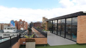 Eine Dachterrasse mit Blick auf die Stadtlandschaft, mit einem modernen Gebäude, das große Fenster und eine Ziegel-Fassade hat.