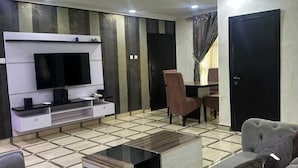 Un salon moderne avec un téléviseur à écran plat, un canapé, une table basse et un fauteuil.