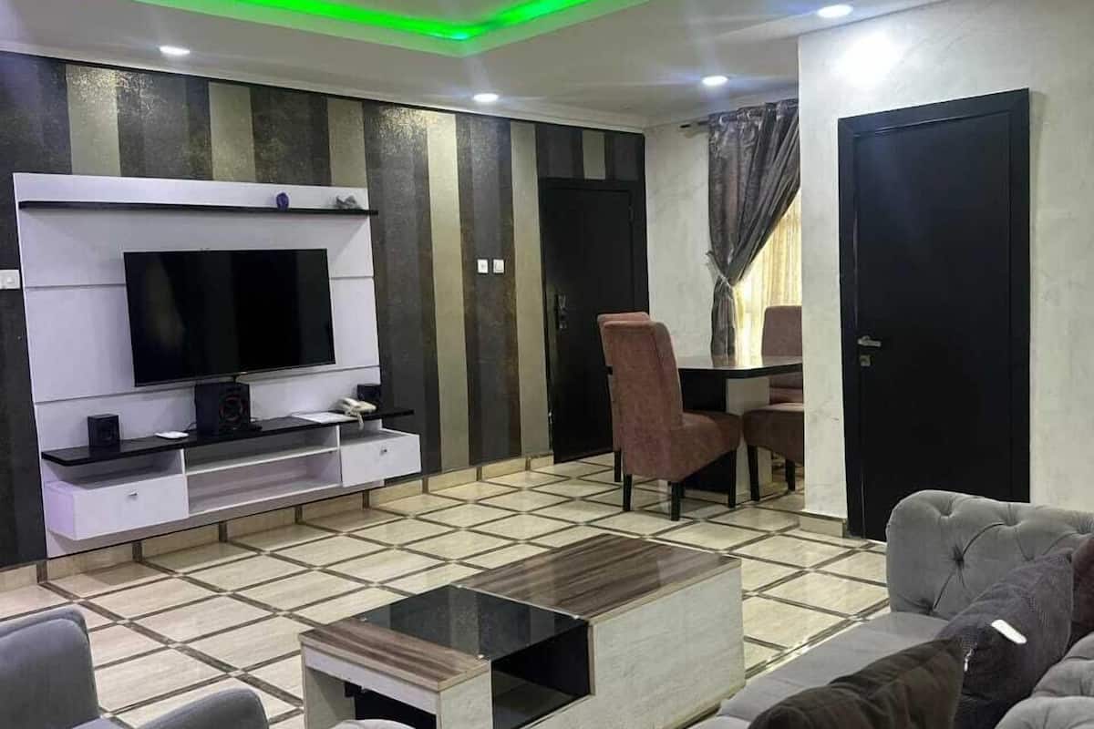 Una sala moderna con televisor de pantalla plana, un sofá, una mesa de centro y una silla.