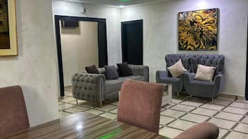 Un soggiorno moderno con un grande tavolo di legno, due divani e un quadro astratto dai colori vivaci appeso al muro.