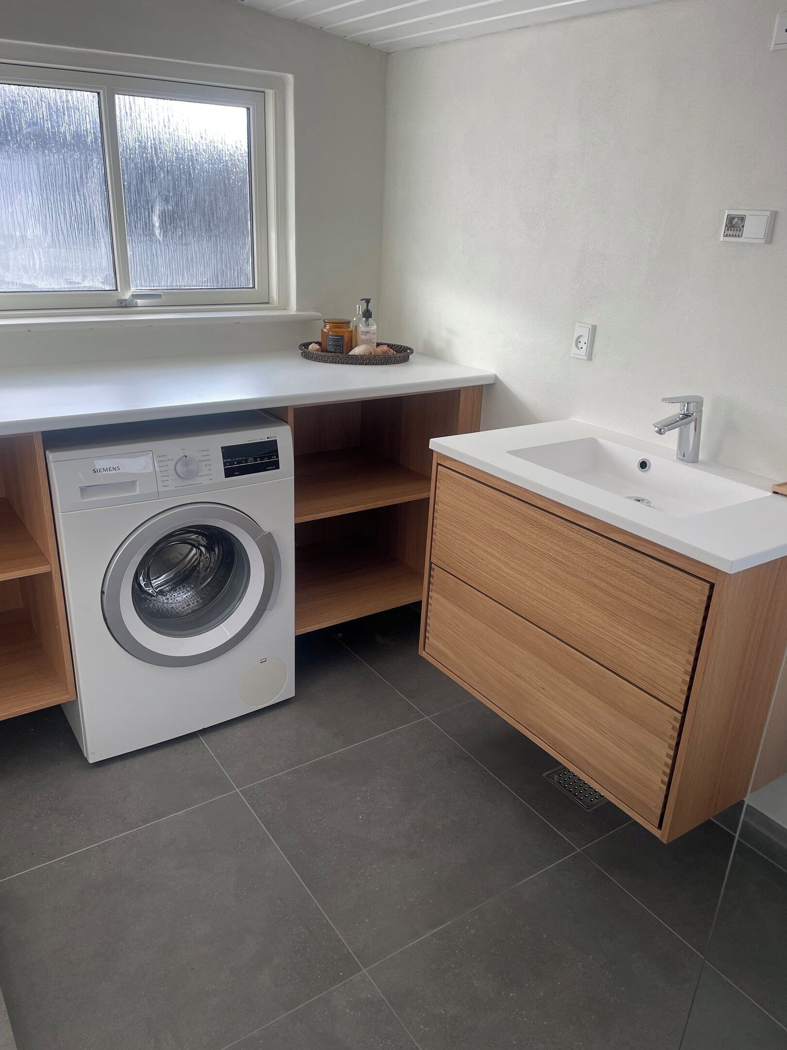 Une petite buanderie équipée d’un lave-linge, d’un évier et d’une fen être.