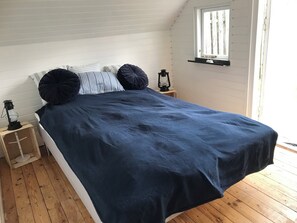 A bedroom with a bed, a nightstand, a lantern, and a window. - Lovely holiday home 80 m from the water (Otterup)