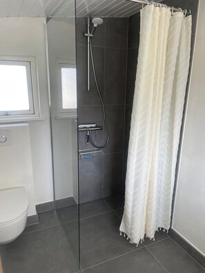 A bathroom with a glass shower enclosure, a toilet, and a window. - Lovely holiday home 80 m from the water (Otterup)