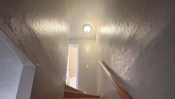 A staircase with wooden steps and a handrail, leading to a door at the top. - Near Fort Sill Cozy 2-Bedroom Townhouse (Lawton)
