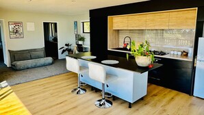 Una cocina moderna con una isla central, armarios negros y un ventanal con vistas a un jardín.