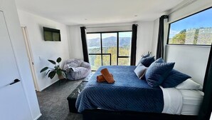 Un dormitorio con una cama grande, vistas a las montañas y una planta.