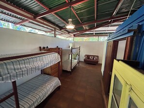 A dormitory room with bunk beds, a small sofa, and a yellow cabinet. - Montezuma Nicoya Peninsula 3 bedroom house with pool in tropical paradise (Las Delicias, Cobano)