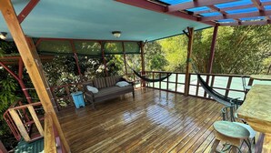 A wooden deck with a hammock, a sofa, and a table. - Montezuma Nicoya Peninsula 3 bedroom house with pool in tropical paradise (Las Delicias, Cobano)