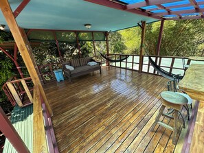 Eine Holzterrasse mit einer Hängematte, einer Couch und einem Tisch.