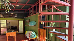 A room with a foosball table, a surfboard, and a staircase. - Montezuma Nicoya Peninsula 3 bedroom house with pool in tropical paradise (Las Delicias, Cobano)