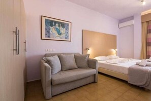 Una habitación de hotel con una cama, un sofá, un cuadro en la pared y una ventana con cortinas.