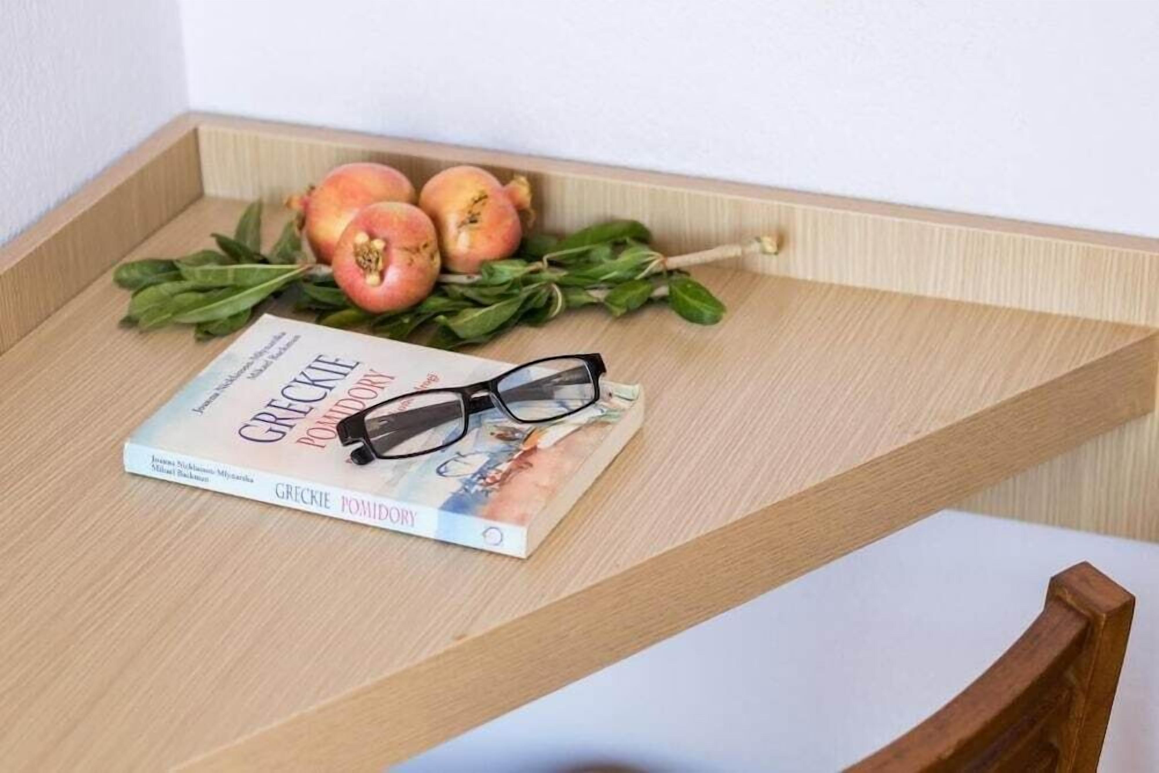 Una bandeja de madera con un libro titulado 'Greekie Pomidor' y un par de gafas encima.