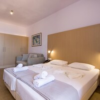 Habitación de hotel con una cama grande, un sofá, un armario y un cuadro en la pared.