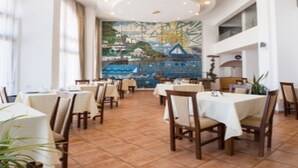 Un restaurante con varias mesas y sillas, un mural en la pared y un piso de baldosas.
