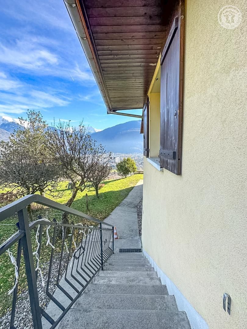 Un escalier menant à un balcon d’où l’on peut admirer une vue sur les montagnes et un ciel dégagé.