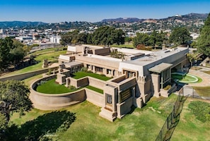 A large, modern building with a central courtyard, surrounded by greenery and a clear view of the cityscape in the background. - Front-Row Hollywood Sign Views -Modern Glass Villa (Los Angeles)
