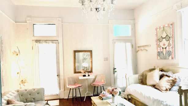 A well-lit bedroom with a bed, a desk, a chair, and a chandelier.