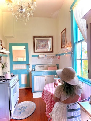 A kitchen with a stove, sink, and a window with curtains.