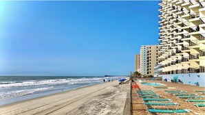 A beach with a wooden walkway and a pool area with lounge chairs. - Beachfront condo w/ balcony in wonderful Garden City Beach (Murrells Inlet)