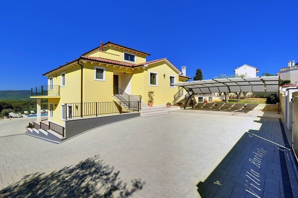 A yellow building with a red roof, a covered outdoor area, and a paved walkway. - Villa Rachele by Istrabook (Rakalj)