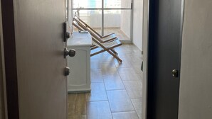 A hallway with a door on the right, a white appliance on the left, and a view of a balcony with clothes drying. - Ocean view apartment (Cartagena de Indias)