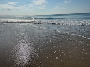 A beach with waves approaching the shore, clear skies, and a calm sea. - Otter Oasis - Serene 3bd pet-friendly sound views (Surf City)