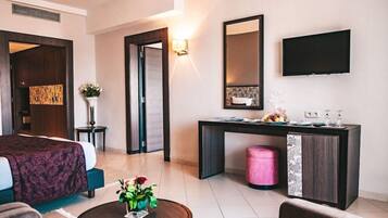 A hotel room with a bed, a desk, a television, and a small table with flowers.