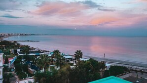 A coastal view with a beach, palm trees, and a clear sky.