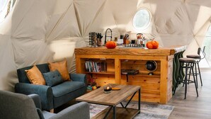 Un interior acogedor con sofá, mesa de centro y una zona de bar de madera con taburetes.