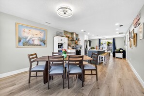 Eine moderne Küche mit Holzausbau, einem Essbereich mit Tisch und Stühlen sowie einem Bild an der Wand.