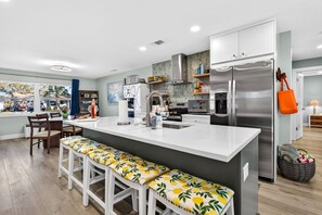 Una cocina moderna con una isla grande, electrodomésticos de acero inoxidable y vistas al exterior.