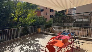 An outdoor patio with a table and chairs, surrounded by a metal fence and trees. - Denina67 - ChiacchioProperty (Rome)