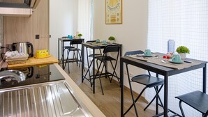 A kitchen with a stainless steel sink, a kettle, and a table set with chairs and a small potted plant. - Denina67 - ChiacchioProperty (Rome)