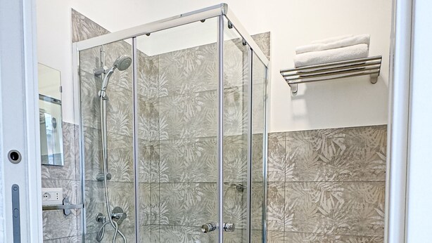 A bathroom with a glass-enclosed shower, a sink, and a toilet. - Denina67 - ChiacchioProperty (Rome)