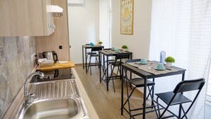 A modern kitchen with a sink, two dining tables, chairs, and a potted plant. - Denina67 - ChiacchioProperty (Rome)