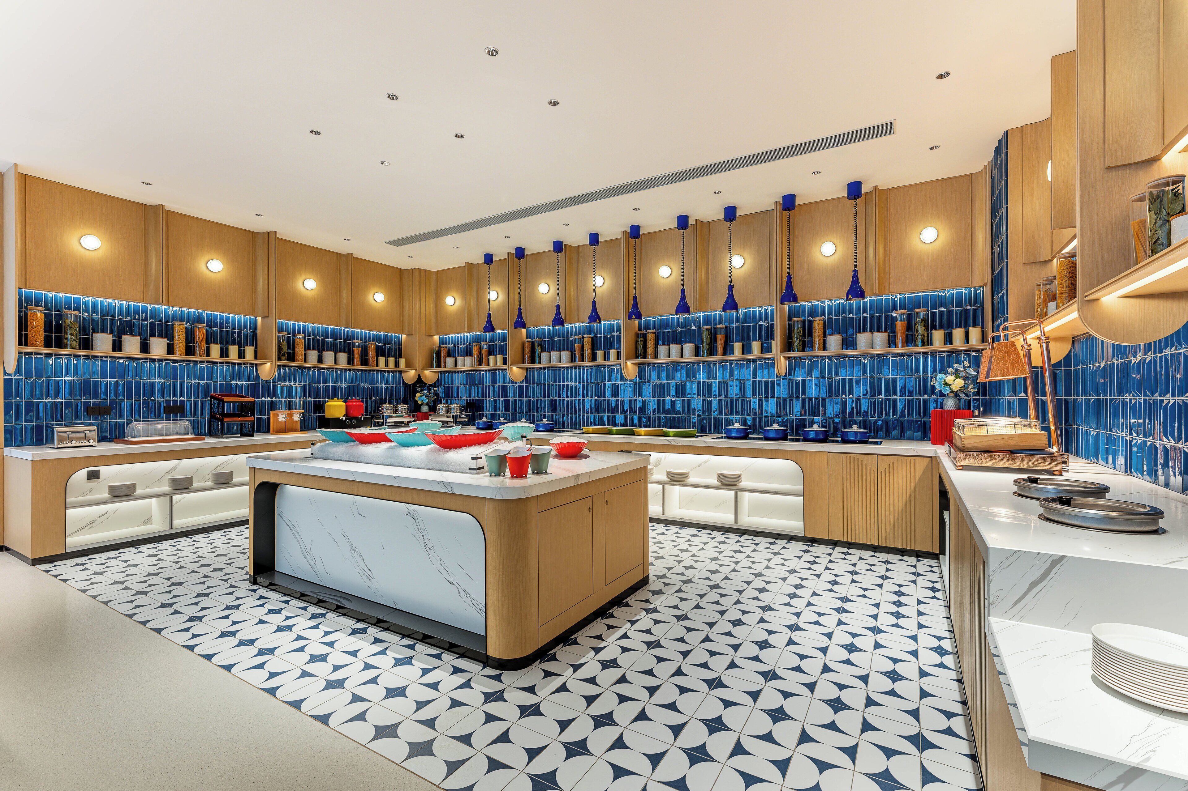 A modern kitchen with a central island, blue tiled backsplash, and wooden cabinetry.