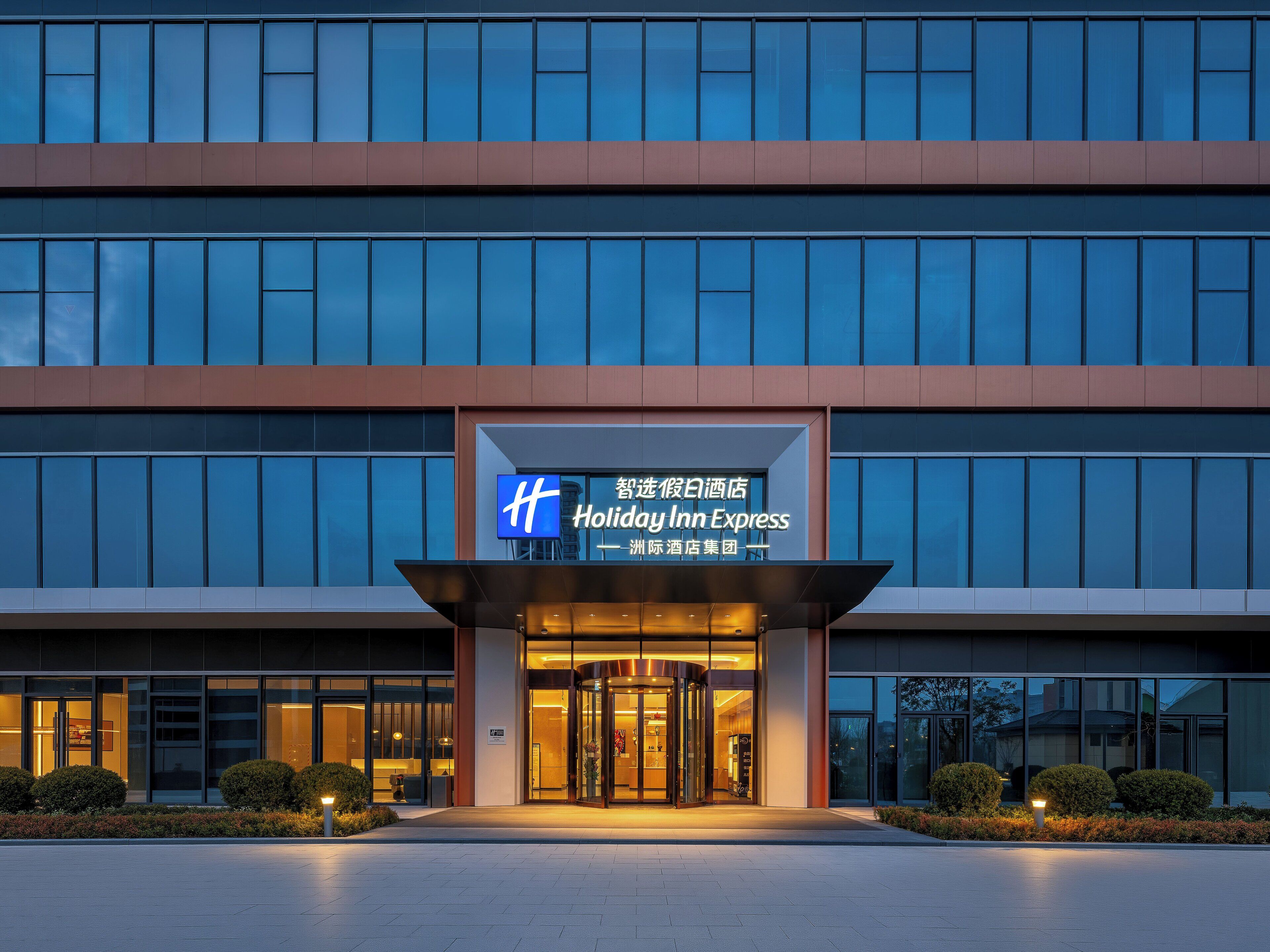 De ingang van een Holiday Inn Express hotel met een modern ontwerp, met een opvallend bord en een glazen gevel.