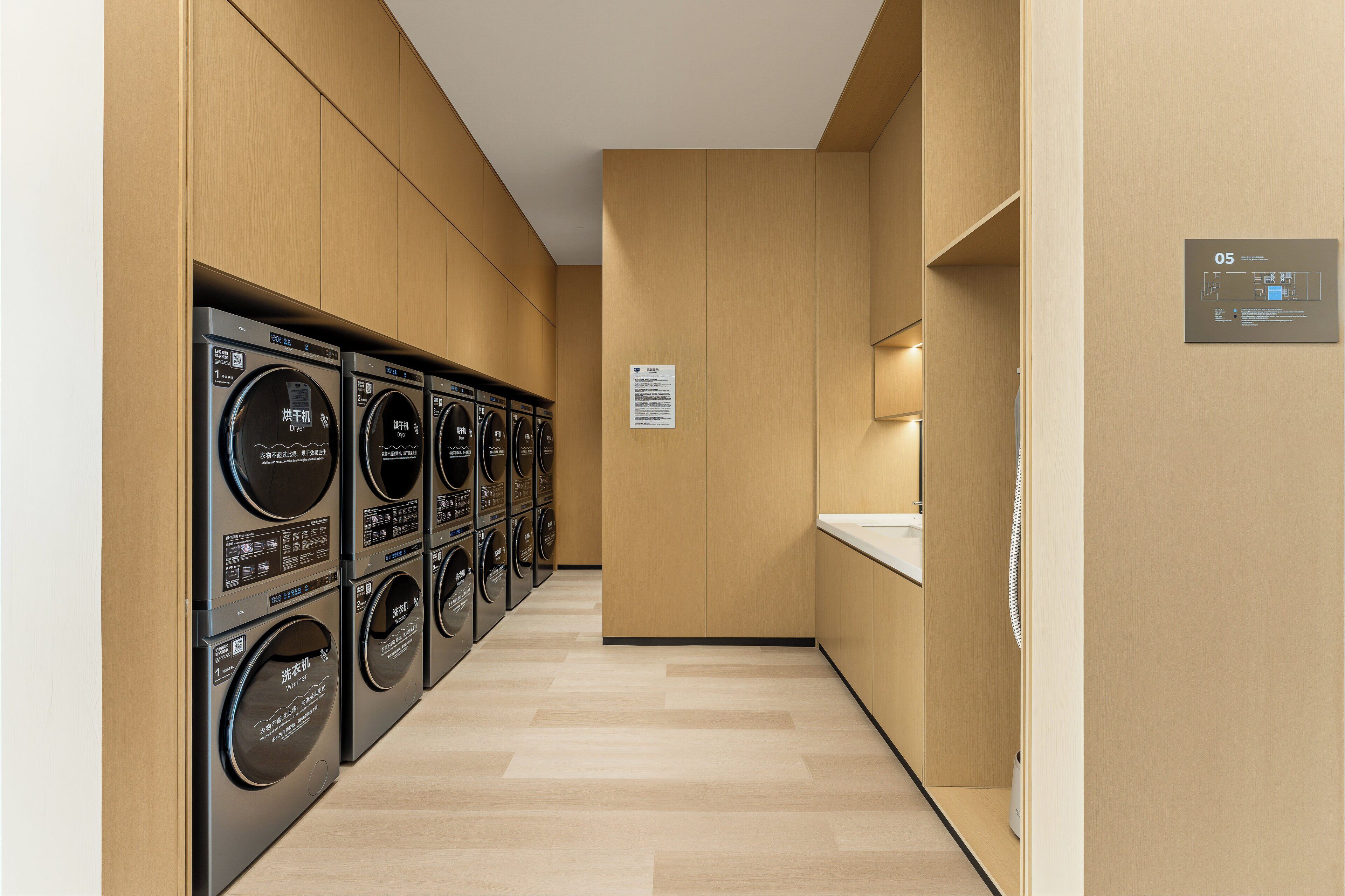 Un cuarto de lavandería con varias lavadoras y secadoras, paredes de madera y un diseño moderno y limpio.