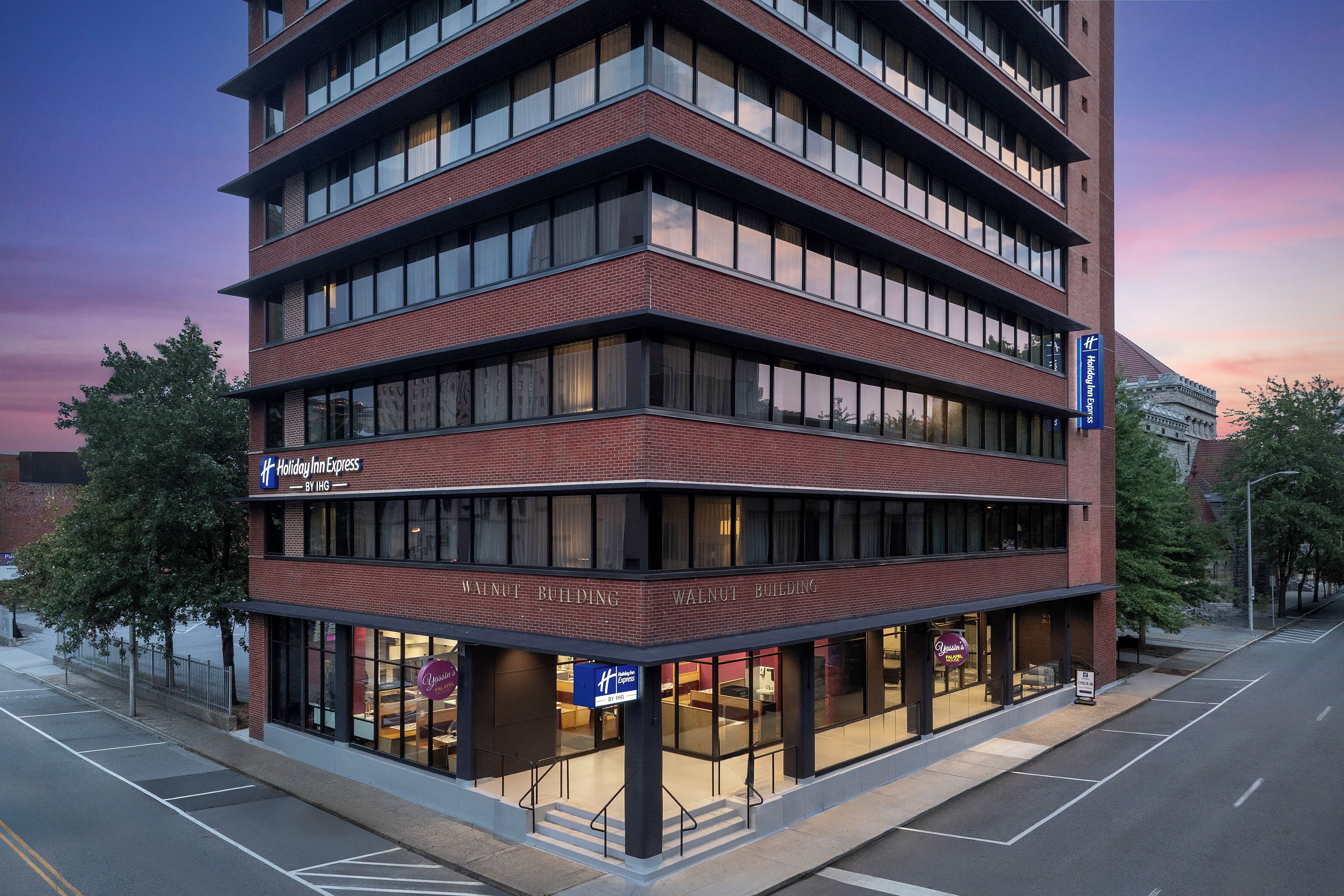 A multi-story hotel with a brick facade, multiple balconies, and a ground-level restaurant.