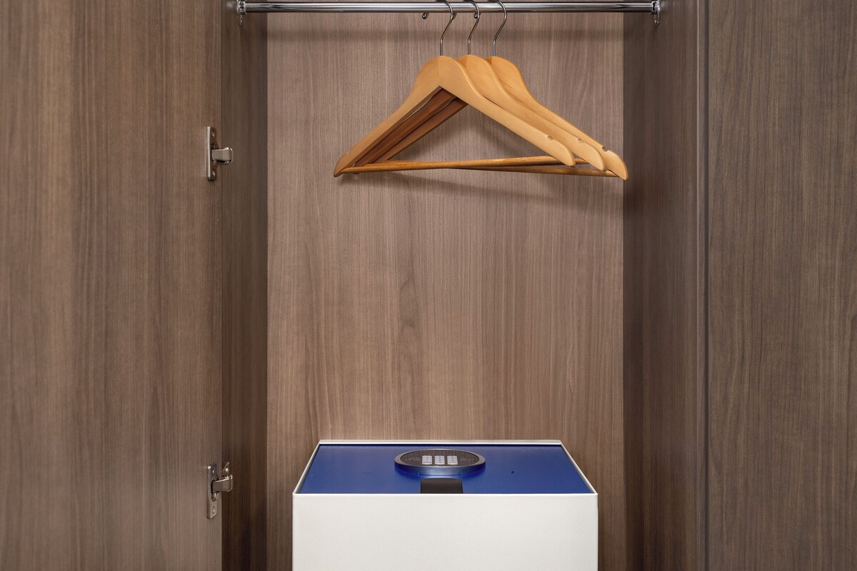 A wardrobe with a hanging rack and a compact blue and white appliance, likely a heater or air purifier, on the floor.