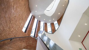 A modern interior with a curved staircase, a brick wall, and a white ceiling with recessed lighting. - Spacious 2 bed apt Near Media City and Old Trafford (Salford)