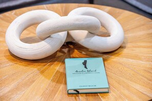 Ein Holztisch mit einer weißen, gedrehten Skulptur und einem Gästebuch mit der Aufschrift 'Amelia Island Welcome to Our Beach House.'