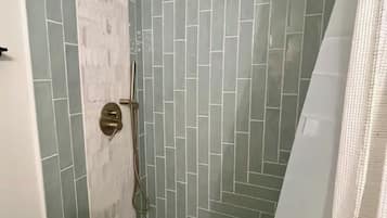 A shower with a handheld showerhead and a handheld shower attachment.
