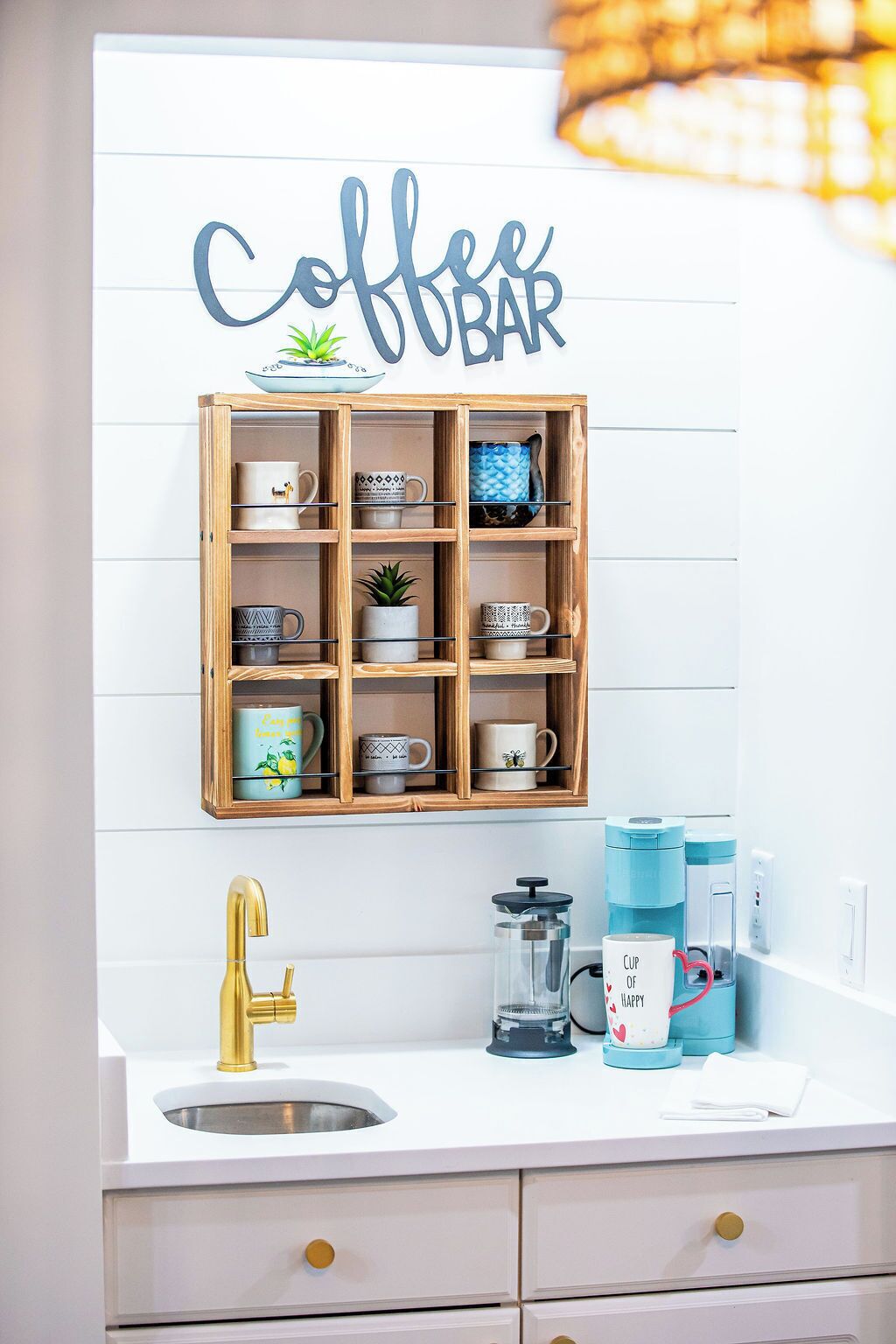 Una cucina con insegna per la caffetteria, una mensola in legno per tazze, un rubinetto dorato e attrezzatura per la preparazione del caffè.