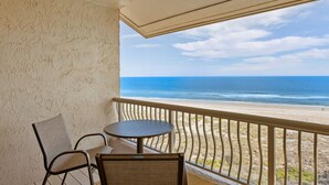 Een balkon met uitzicht op strand en zee.